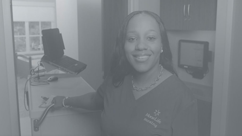 Black-and-white photo of a Morselife healthcare professional smiling at a reception desk with medical equipment nearby