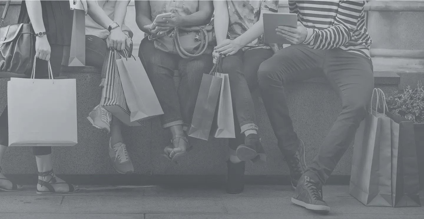 Black-and-white image of people sitting with shopping bags