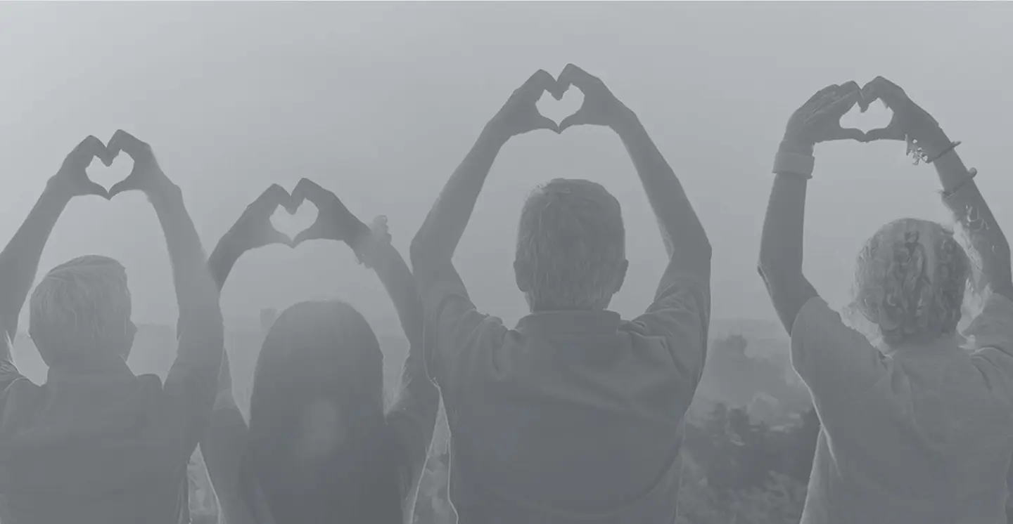 Black-and-white image of a group of people forming heart shapes with their hands