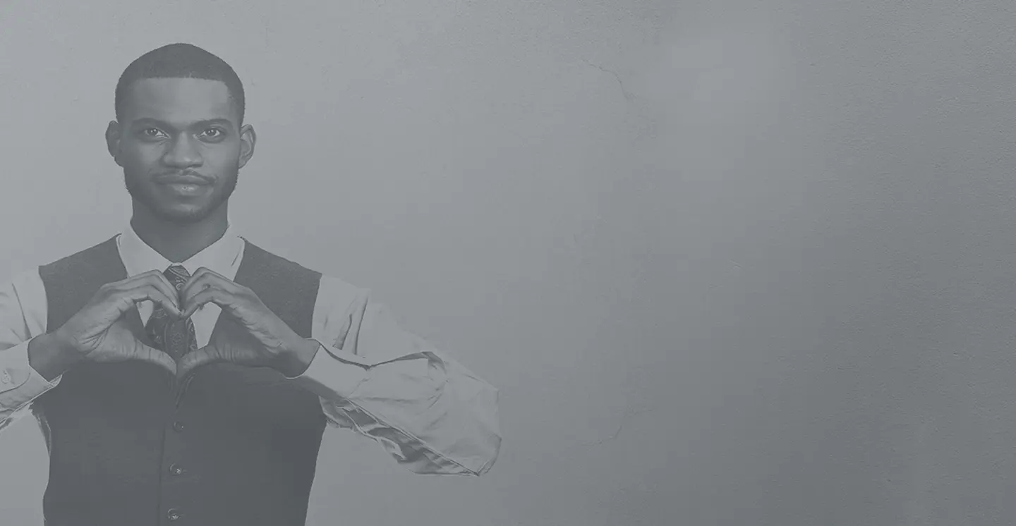 A man dressed professionally showing the heart sign with his hands